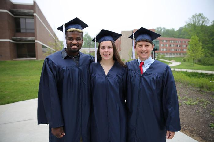 三个学生在毕业典礼后微笑.